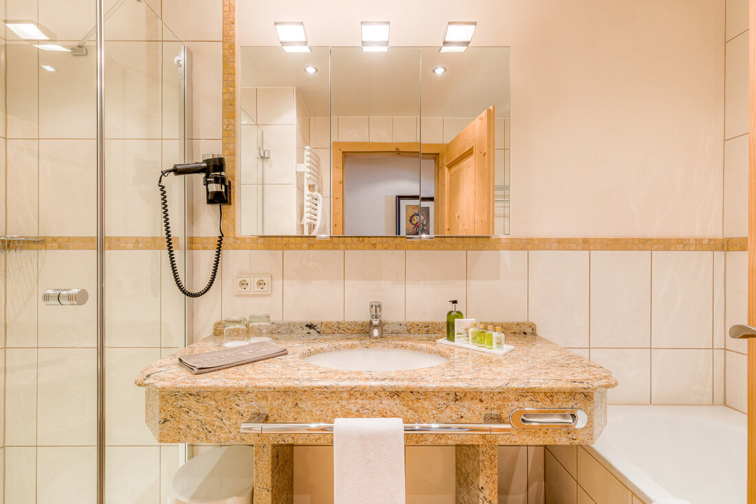 Ein modernes Badezimmer mit einem eleganten Granitwaschtisch und einem großen Spiegel, der den Raum reflektiert.