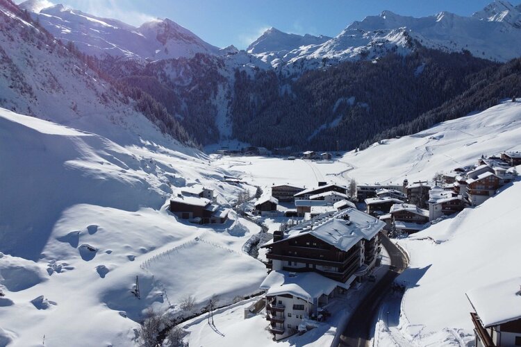 Das Dorf im Schnee strahlt Ruhe aus, während die schneebedeckten Berge im Hintergrund eine beeindruckende Kulisse bieten.