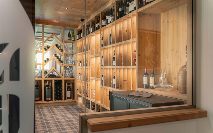 Der Weinkeller bietet eine harmonische Kombination aus Holzregalen und Weinflaschen, die in sanftem Licht erstrahlen.
