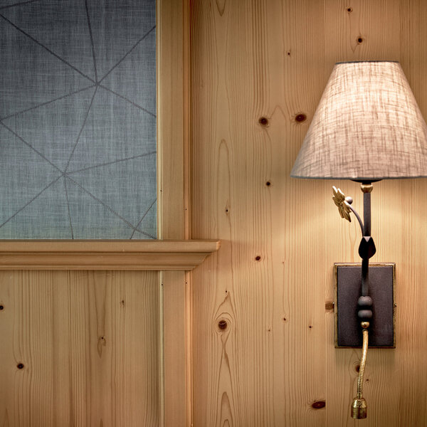 Eine elegante Wandleuchte mit einem schlichten Lampenschirm aus Stoff, die an einer Holzwand montiert ist.