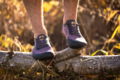 Ein Mann mit violetten Schuhen steht auf einem liegenden Baumstamm.