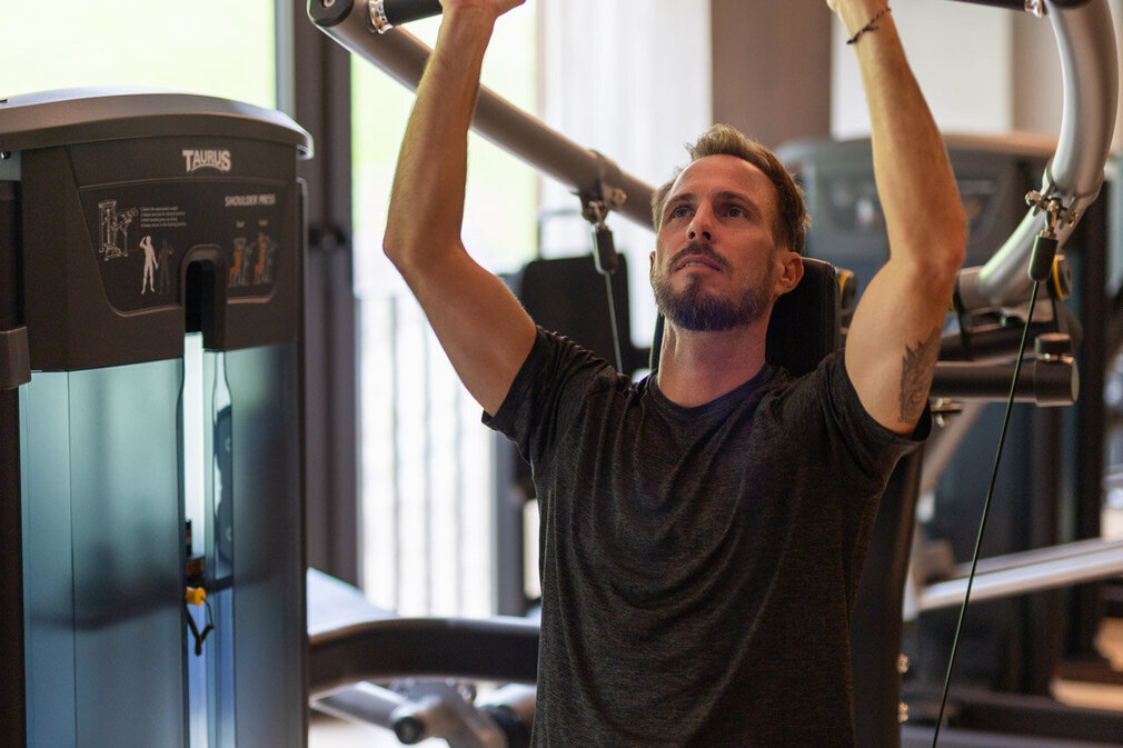 Ein Mann trainiert an einem Gerät im Fitnessstudio.