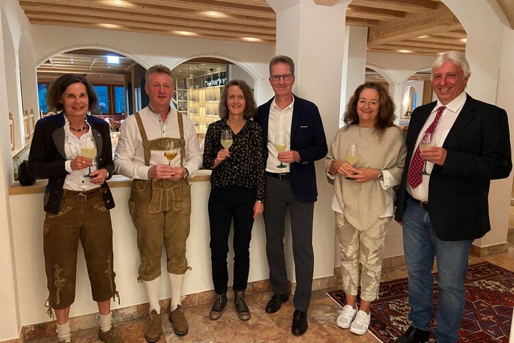 In einem stilvollen Restaurant posieren fünf Erwachsene in festlicher Kleidung, während sie Drinks in der Hand halten.