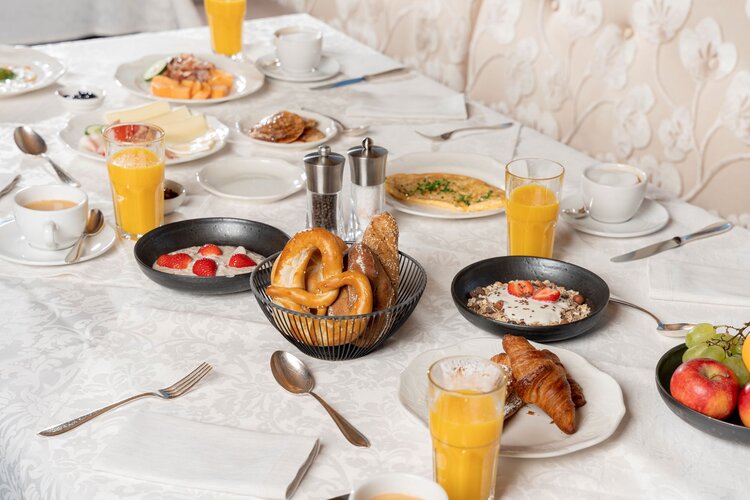 Ein reichhaltiges Frühstücksbuffet mit frischen Brötchen, Croissants, Obst und verschiedenen Getränken auf einem eleganten Tisch.