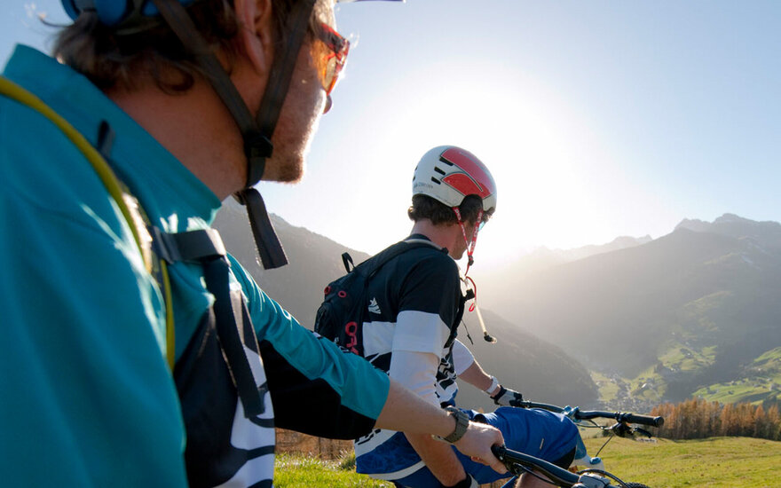 Zwei Radfahrer genießen die Aussicht auf die Berge und das Tal im Zillertal bei strahlendem Sonnenschein.