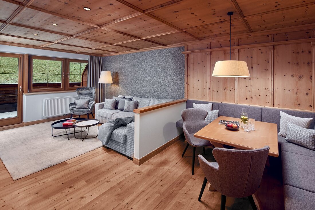 Ein stilvolles Wohnzimmer mit Holzdecke, gemütlichem Sofa und einem Esstisch, der mit Obst und Getränken dekoriert ist.