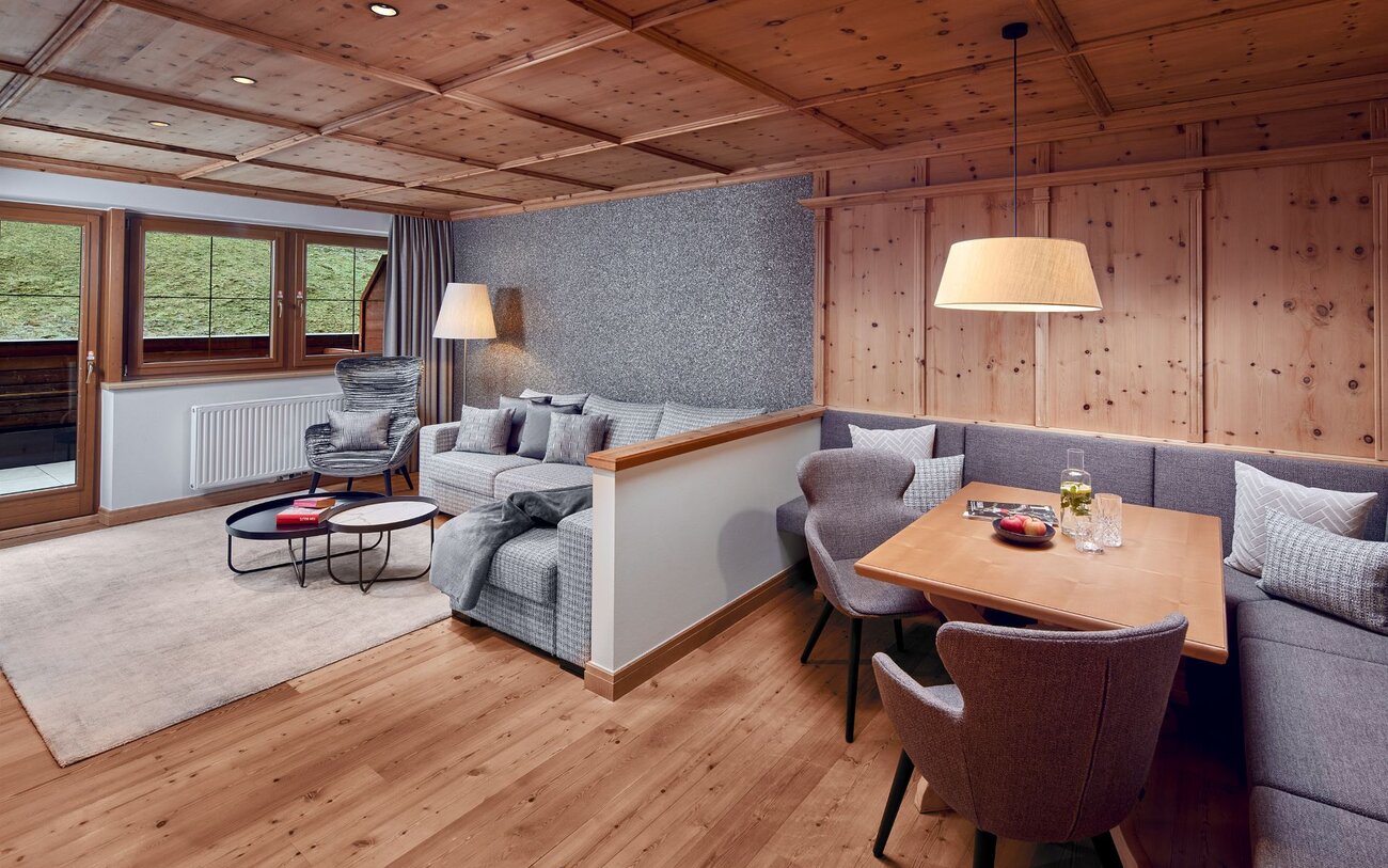 Ein stilvolles Wohnzimmer mit Holzdecke, gemütlichem Sofa und einem Esstisch, der mit Obst und Getränken dekoriert ist.