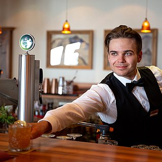 Barmann hinter der Bar stellt einen Cocktail auf die Theke 