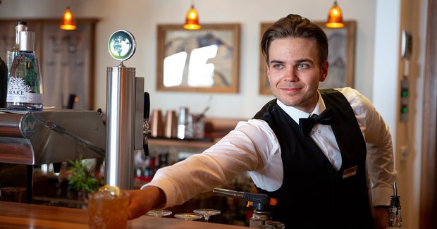 Barmann hinter der Bar stellt einen Cocktail auf die Theke 